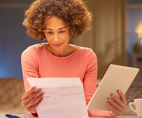 young woman with an iPad is looking at a bill