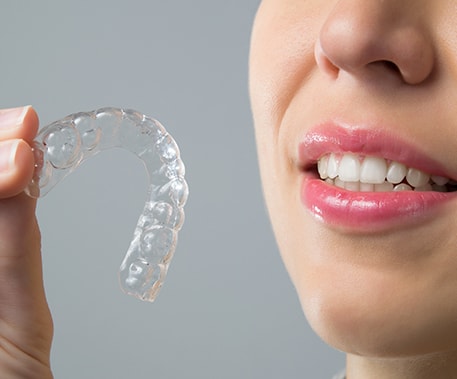 woman is holding Invisalign® braces