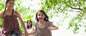 Two young sisters smiling and laughing while running around outside